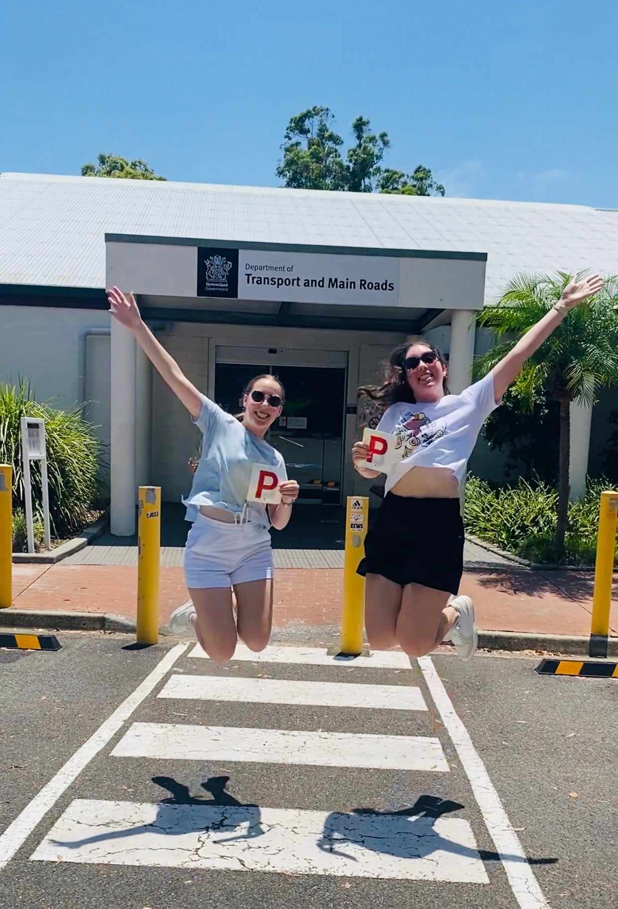 Beaming new drivers holding up their Gold Coast driving test pass certificate.