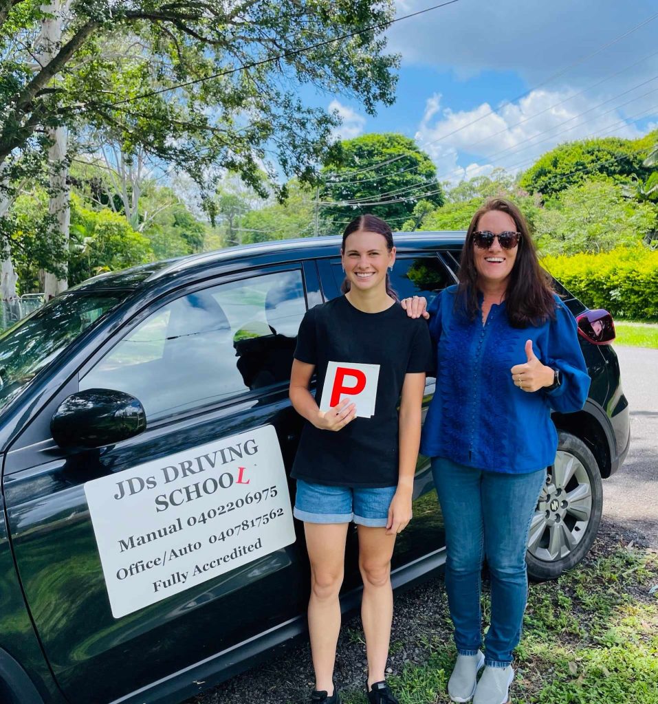 Joyful learner in JDS Driving School vehicle showcasing a 'P' sign.