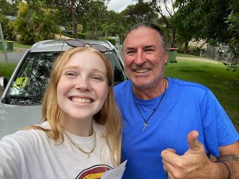 Excited student giving thumbs up outside JDS Driving School car after passing the test.